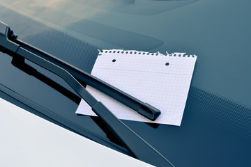 sheet of paper under a windshield wiper