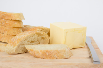 Ciabatta bread slices and piece of butter on the cutting board