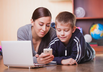 mom and son are lying on wood flooring with laptop