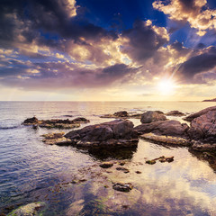 Obraz premium sea wave breaks about boulders at sunset
