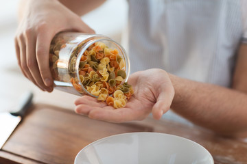 close up of male emptying jar with colorful pasta