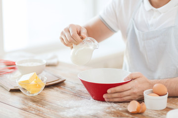 close up of male hand pouring milk in bowl