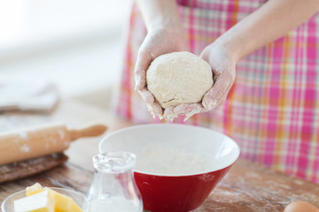 close up of female hands kneading dough at home