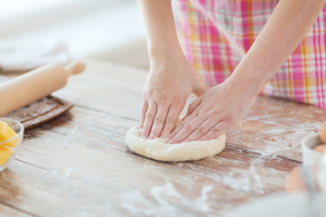 Obraz na płótnie Canvas close up of female hands kneading dough at home