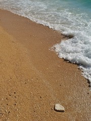 Waves on beautiful beach with sand and rock in Podgora, Croatia