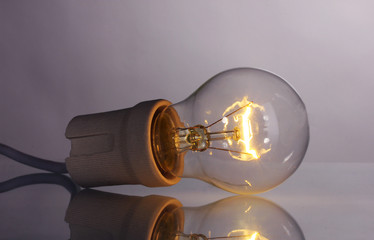 A lit light bulb on grey