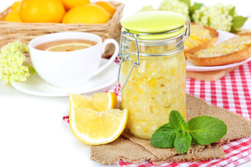 Tasty lemon jam with cup of tea on table close-up