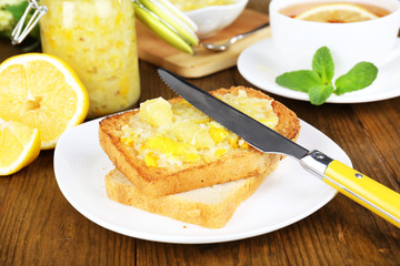 Delicious toasts with lemon jam on plate on table close-up