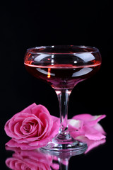 Composition with pink sparkle wine in glass and  rose isolated