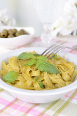 Delicious pasta with pesto on plate on table on light