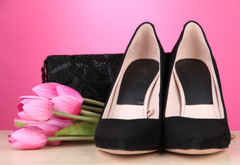 Obraz na płótnie Canvas Beautiful black female shoes, bag and flowers on pink