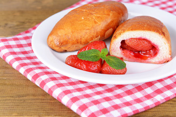Fresh baked pasties with strawberries on plate on table