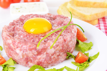 Delicious steak tartare with yolk on plate on table close-up