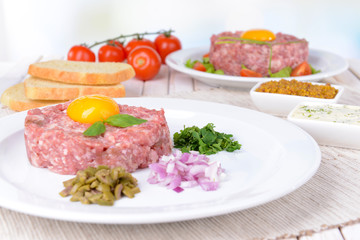 Delicious steak tartare with yolk on plate on table close-up