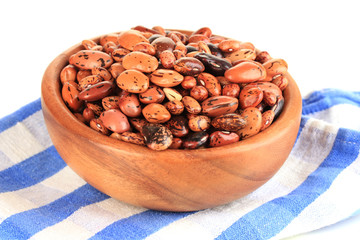 Raw beans in bowl on color napkin, isolated on white