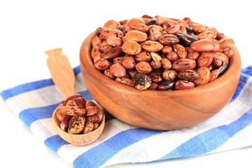 Raw beans in bowl on color napkin, isolated on white