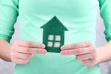 Little paper house in hand close-up, on light background