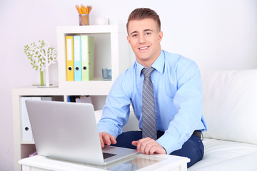 Handsome young man working on laptop at home