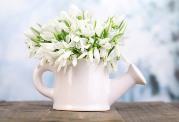 Beautiful snowdrops in vase, on table on bright background