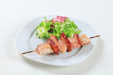 Pork skewer with salad greens