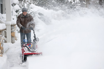 Man clearing driveway with snowblower © Elenathewise