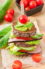 Sandwich with ham and fresh vegetables on a wooden background