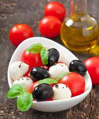 Fresh salad with cherry tomatoes, basil, mozzarella and olives