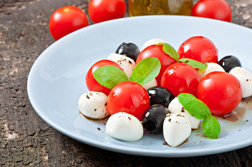 Fresh salad with cherry tomatoes, basil, mozzarella and olives