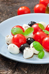 Fresh salad with cherry tomatoes, basil, mozzarella and olives
