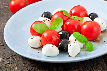 Fresh salad with cherry tomatoes, basil, mozzarella and olives