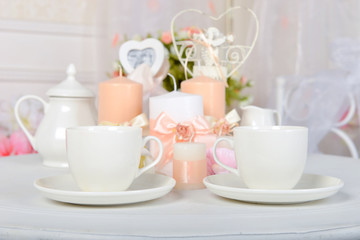 Coffee cups and candles on a white table. Romantic dinner.