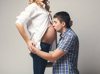 Portrait of young man kissing pregnant wife's belly