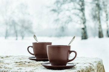 Two cups of tea on background of a winter landscape