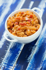 Glass bowl with braised cabbage, blue wooden background