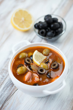 Russian soup solyanka served with olives and lemon