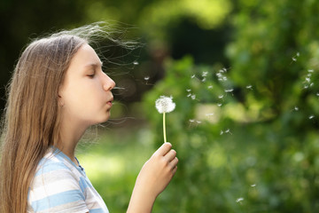 teenage girl blowing a dandelion