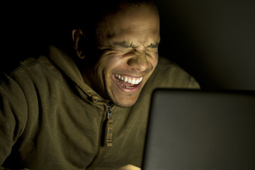 Man laughing on his laptop late at night