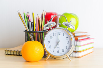 Back to school , note book , clock , pencil , apple on wood tabl