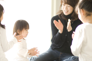 Three Japanese sisters and mother clapping their hands and playing