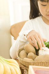 Obraz na płótnie Canvas Japanese daughter taking vegetables from basket in kitchen