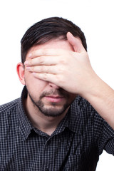 Young man with hand over his eyes isolated on white background