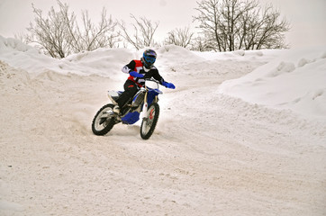 Winter motocross racer on a motorcycle turns with the slope and