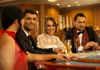 Group of happy young people behind gambling table with drinks