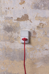 White socket with red wire on grungy wall