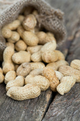 peanuts in a miniature burlap bag on wooden surface