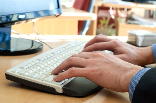Man's hands upon a white keyboard. Typing