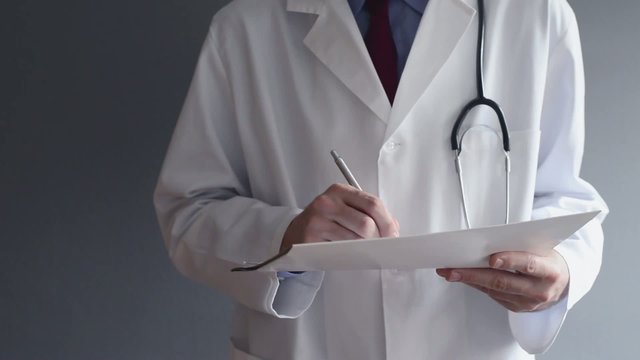 Male doctor writing prescription while standing.