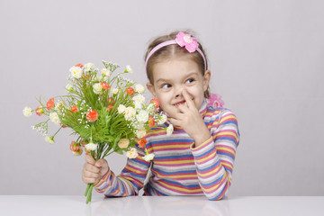Obraz na płótnie Canvas девочка с букетом цветов сидит за столом