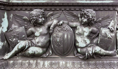 Fototapeta premium Bronze relief of cherubs holding shields