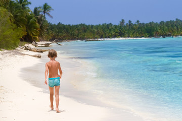 Fototapeta na wymiar Little boy walking on a beautiful tropical beach